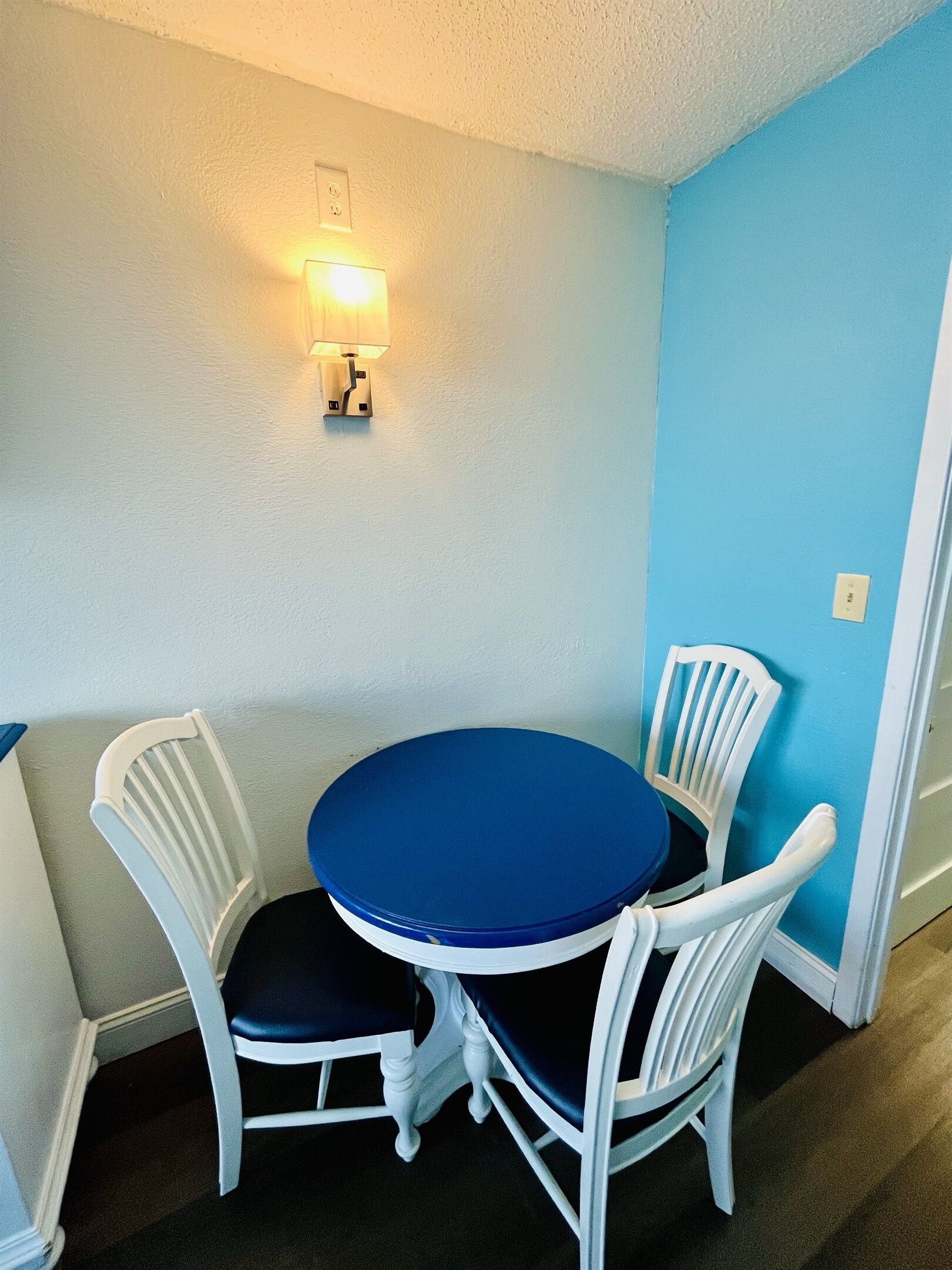 A small dining area with a round table and four white chairs.
