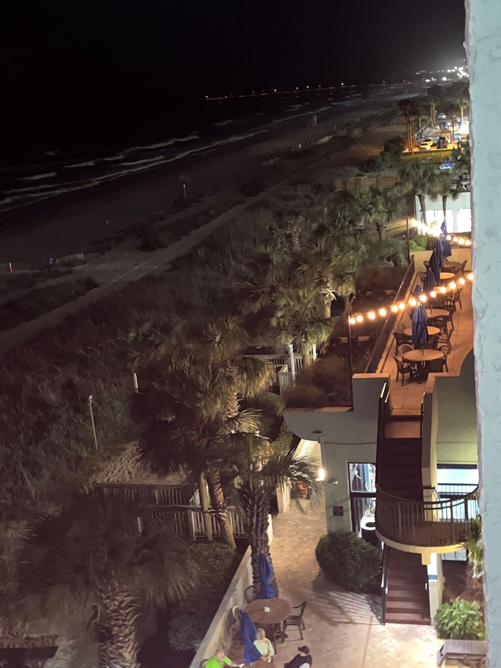 Ein Hotel am Strand bei Nacht, mit Außenbereich und Palmen.