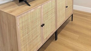 Ein Flachbildfernseher auf einer Holzeinrichtung mit gewobenen Paneelen und schwarzen Griffen.