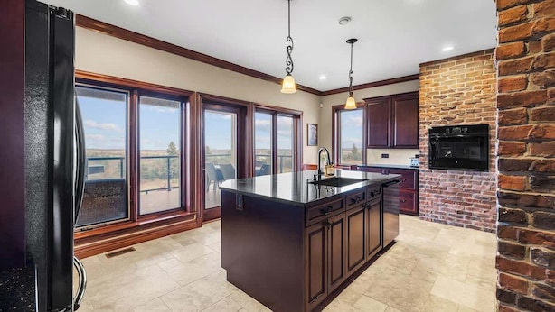 A kitchen with a large island, dark cabinetry, and a brick accent wall. - New Glasgow Pool House - Indoor Pool - Sleeps 14 (New Glasgow)
