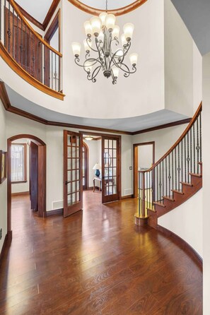 A spacious interior with a grand staircase, a chandelier, and wooden flooring. - New Glasgow Pool House - Indoor Pool - Sleeps 14 (New Glasgow)