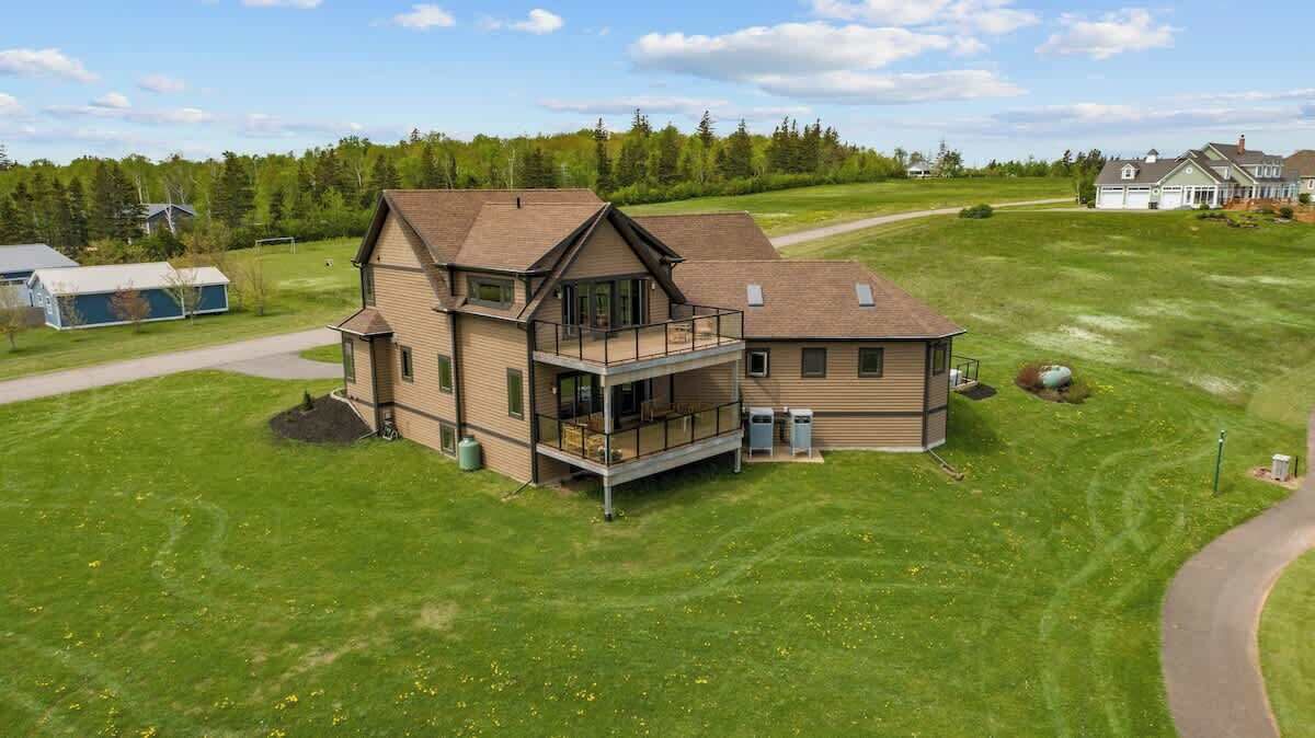 Een ruime, twee verdiepingen tellende woning met een balkon, oprit en een verzorgd gazon.