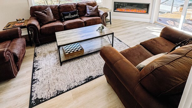 Una sala de estar moderna con sofás de cuero, chimenea, ventana grande y televisor de pantalla plana.