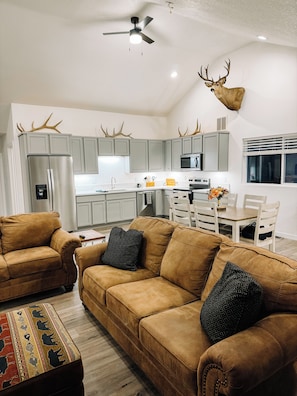 A modern kitchen with grey cabinets, a stainless steel refrigerator, and a mounted deer head.