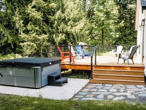 En terrasse med udendørs møbler, en jacuzzi og en sti belagt med sten.