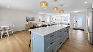 A modern kitchen with a central island, pendant lights, and a refrigerator.