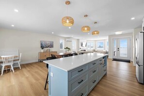 A modern kitchen with a central island, pendant lights, and a refrigerator. - The Lantern Hill Lookout (North Rustico)