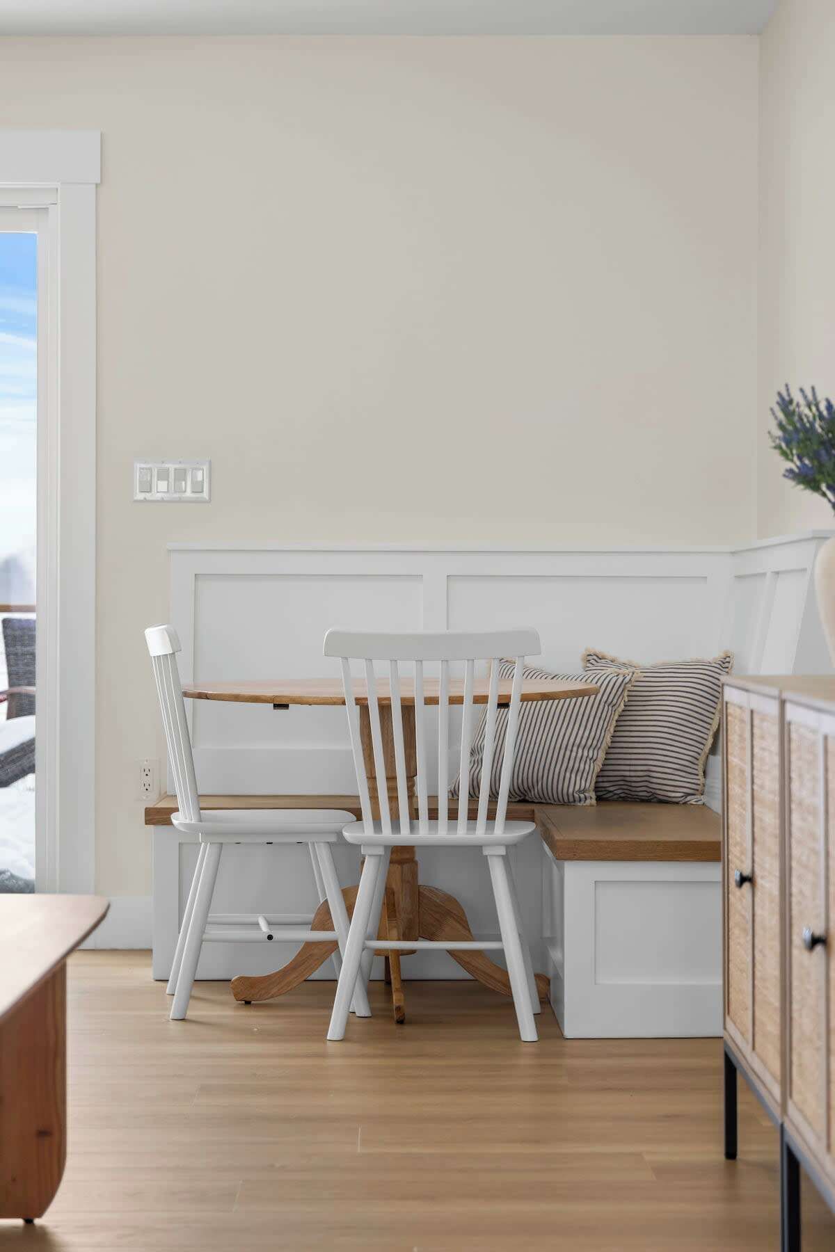 A dining area with a wooden table and chairs, a bench with cushions, and a cabinet.