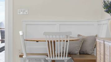 A dining area with a wooden table and chairs, a bench with cushions, and a cabinet.