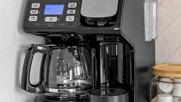 Una cafetera con pantalla digital, jarra de vidrio y bandeja de goteo.
