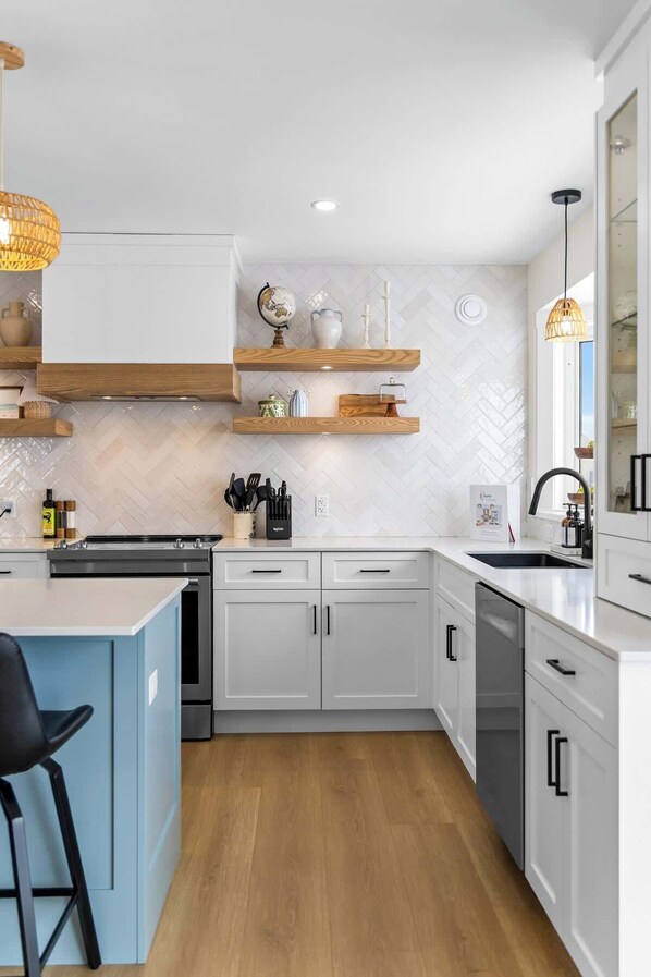 A modern kitchen with white cabinets, wooden countertops, and a central island with bar stools.