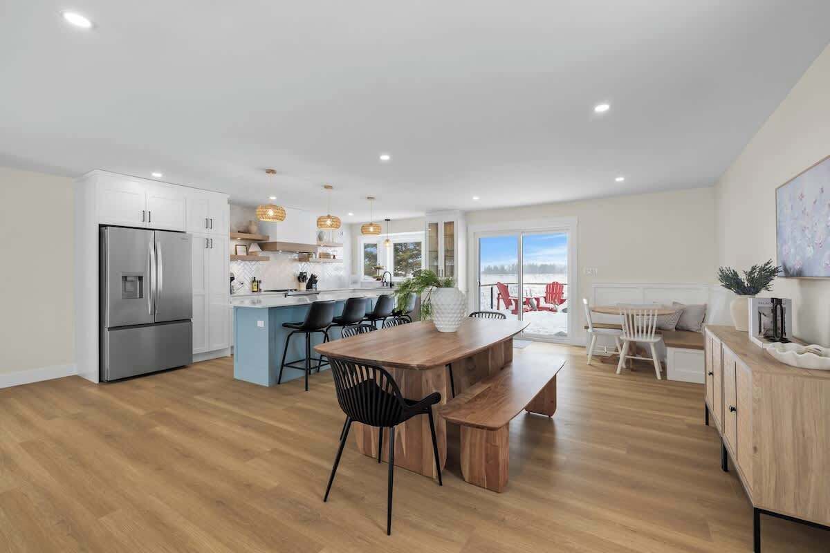 Een moderne keuken met een centraal eiland, een eethoek met een houten tafel en stoelen, en uitzicht op de omgeving.