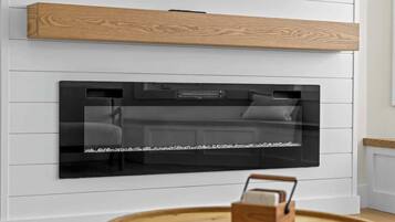 A modern kitchen with a built-in black oven, white wall paneling, and a wooden shelf above.