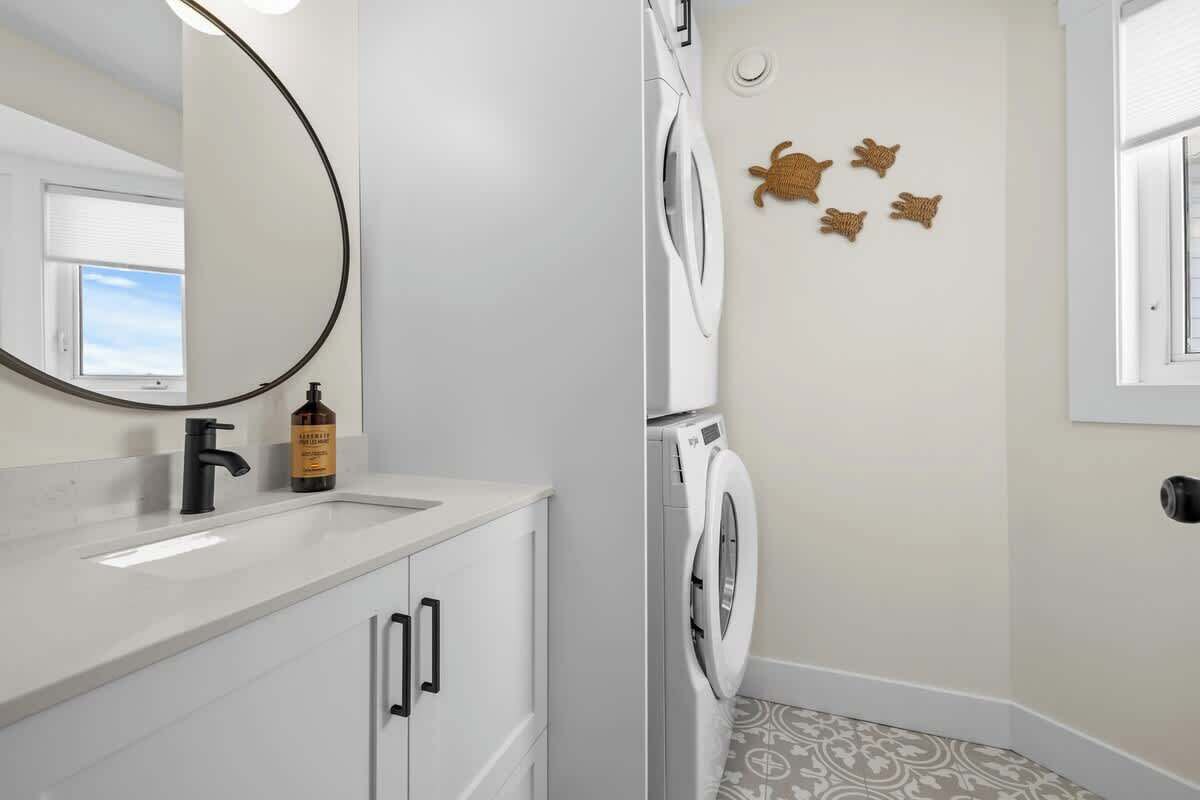 Un bagno moderno con lavandino bianco, uno specchio, una lavatrice e decorazioni murali.