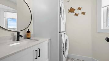 Un bagno moderno con lavandino bianco, uno specchio, una lavatrice e decorazioni murali.