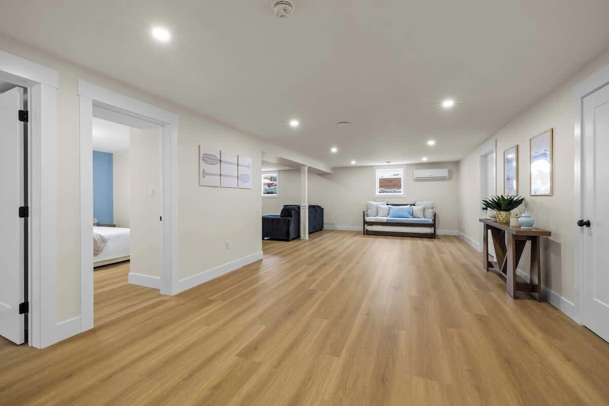 Une pièce spacieuse dotée d’un plancher en bois, d’un canapé, d’une table basse et d’une petite table sur laquelle est posée une plante.