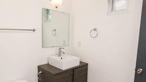 Een badkamer met toilet, wastafel, spiegel en handdoekhouder.