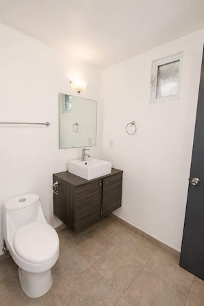 Ein Badezimmer mit Toilette, Waschbecken, Spiegel und Handtuchhalter.