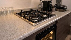 Een moderne keuken met een gasfornuis, koffiezetapparaat en een inbouwoven.