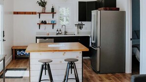 Eine moderne Küche mit Holzbalken, einer zentralen Kochinsel mit Barhocker, einem Kühlschrank und einem Deckenventilator.
