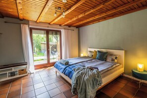 Een slaapkamer met een bed, een bankje, een klein tafeltje en een raam.