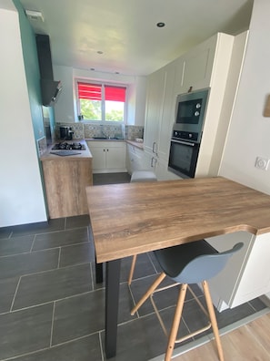 Una cucina moderna con mobili bianchi, un tavolo da pranzo in legno e un forno a incasso.