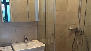 Un baño con ducha compartimentada con vidrio, lavabo, inodoro y espejo sobre el lavabo.