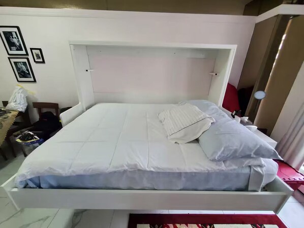 A bed with white bedding, a headboard, and a bedside table with a lamp.