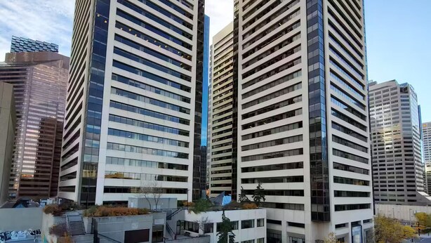 A modern urban building complex with multiple high-rise structures, a parking area, and a pedestrian walkway. - City Center, Murphy Bed & Kitchen 300 Airport bus. private condo with balcony (Calgary)