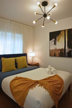 Ein Hotelzimmer mit Bett, Nachttisch, Lampe und einem Bild an der Wand.