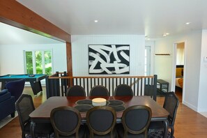 A dining area with a pool table, a large abstract painting, and a staircase leading to another room.
