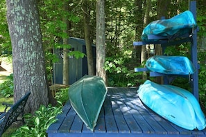 A wooden deck with kayaks and a bench.