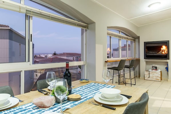 Un coin repas avec une table dressée pour quatre personnes, une cheminée et un téléviseur.