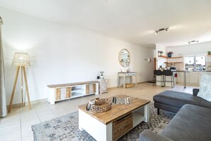 Un salon moderne avec un canapé, une table basse et un coin cuisine à l’arrière-plan.