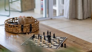 A chessboard on a wooden table with a woven basket and a cup nearby.
