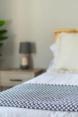 Una cama con una colcha estampada, una lámpara de noche y una mesita de noche de madera.