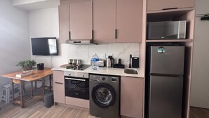 Cocina compacta con lavadora, microondas y televisor de pantalla plana.