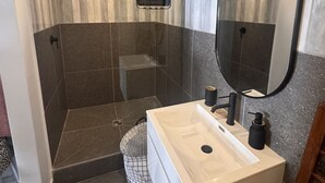 Un baño moderno con ducha, lavamanos y un espejo grande.