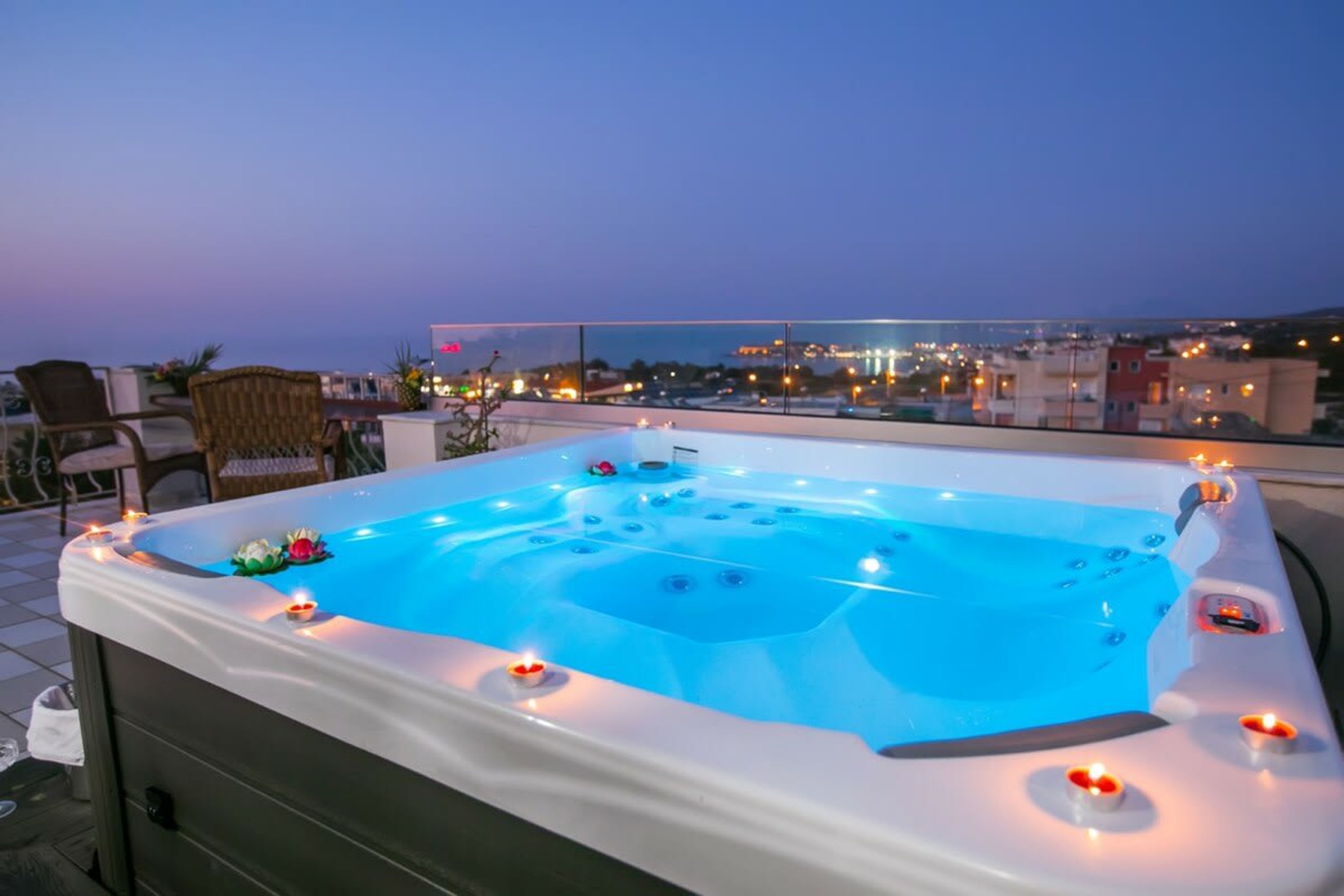 A hot tub with candles on a rooftop terrace with city views.