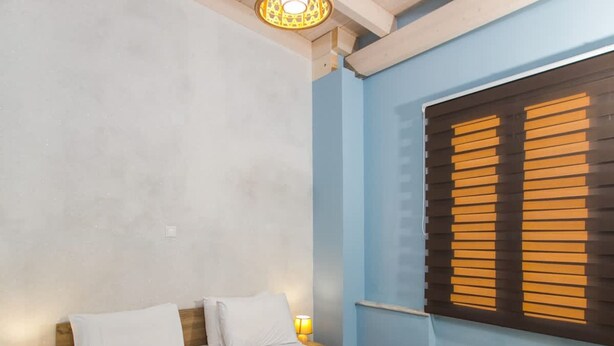 A bedroom with a bed, bedside lamps, a window with blinds, and a wooden ceiling. - Sea and City Views Apartment in Villa Zina (Rethymno)