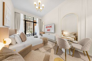 Ein modernes Hotelzimmer mit einem großen Bett, einem Essbereich, einem Fernseher und Blick auf die Stadt.