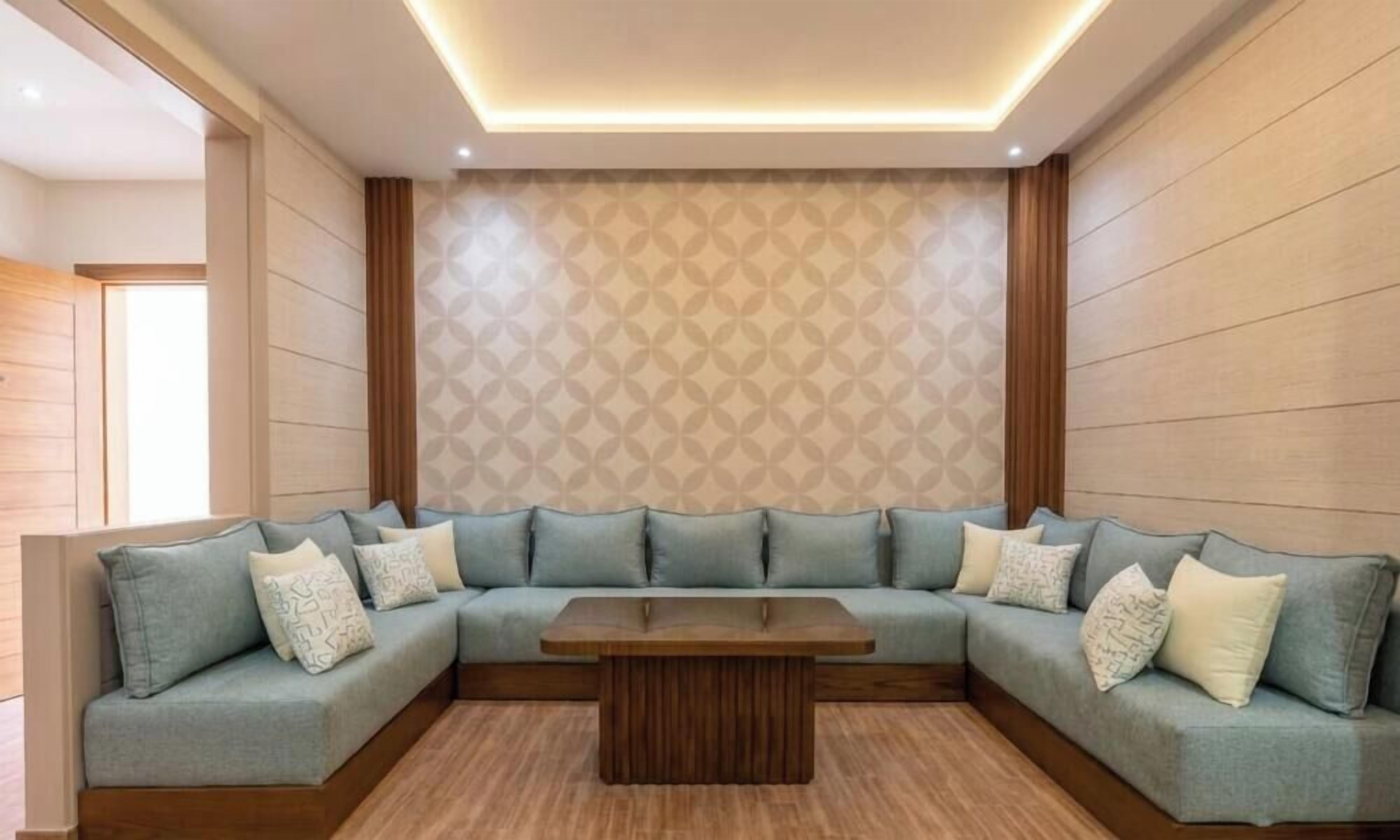 A modern living room with a sectional sofa, a wooden coffee table, and patterned wallpaper.