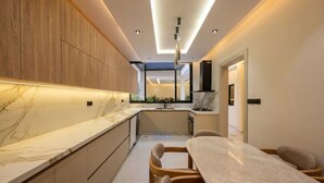 A modern kitchen with a marble countertop, wooden cabinets, and a dining area with a table and chairs. - Spacious 3 Bedroom Apartment in Tangier - Near Stadium, Airport and Beaches (Tanger)