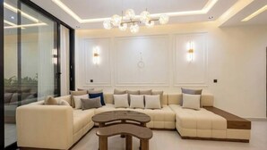 A modern living room with a sectional sofa, a coffee table, and a chandelier. - Spacious 3 Bedroom Apartment in Tangier - Near Stadium, Airport and Beaches (Tanger)