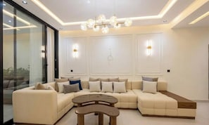 A modern living room with a sectional sofa, a coffee table, and a chandelier. - Spacious 3 Bedroom Apartment in Tangier - Near Stadium, Airport and Beaches (Tanger)