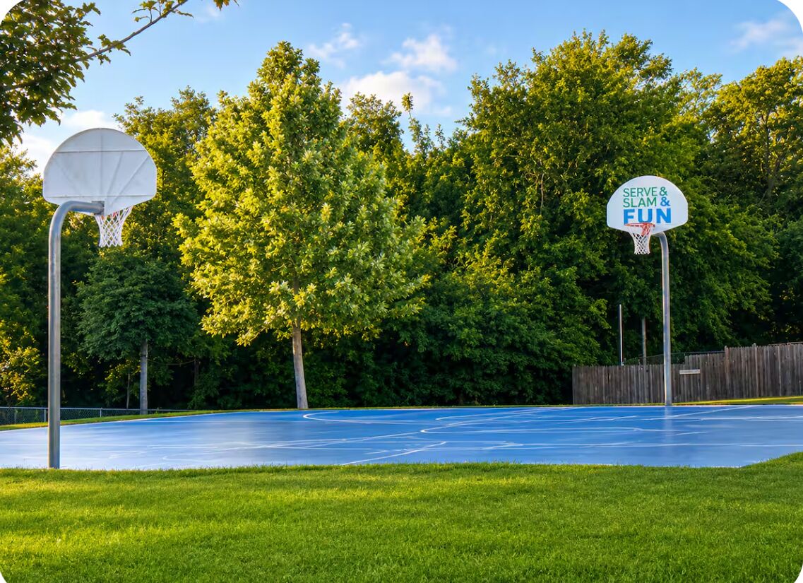 Een buitenbasketbalveld met een ring en een bord waarop staat 'SERVE & SLAM & FUN'.