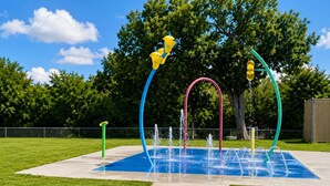 Ein Wasserspielplatz mit mehreren Fontänen und bunten Bauwerken.