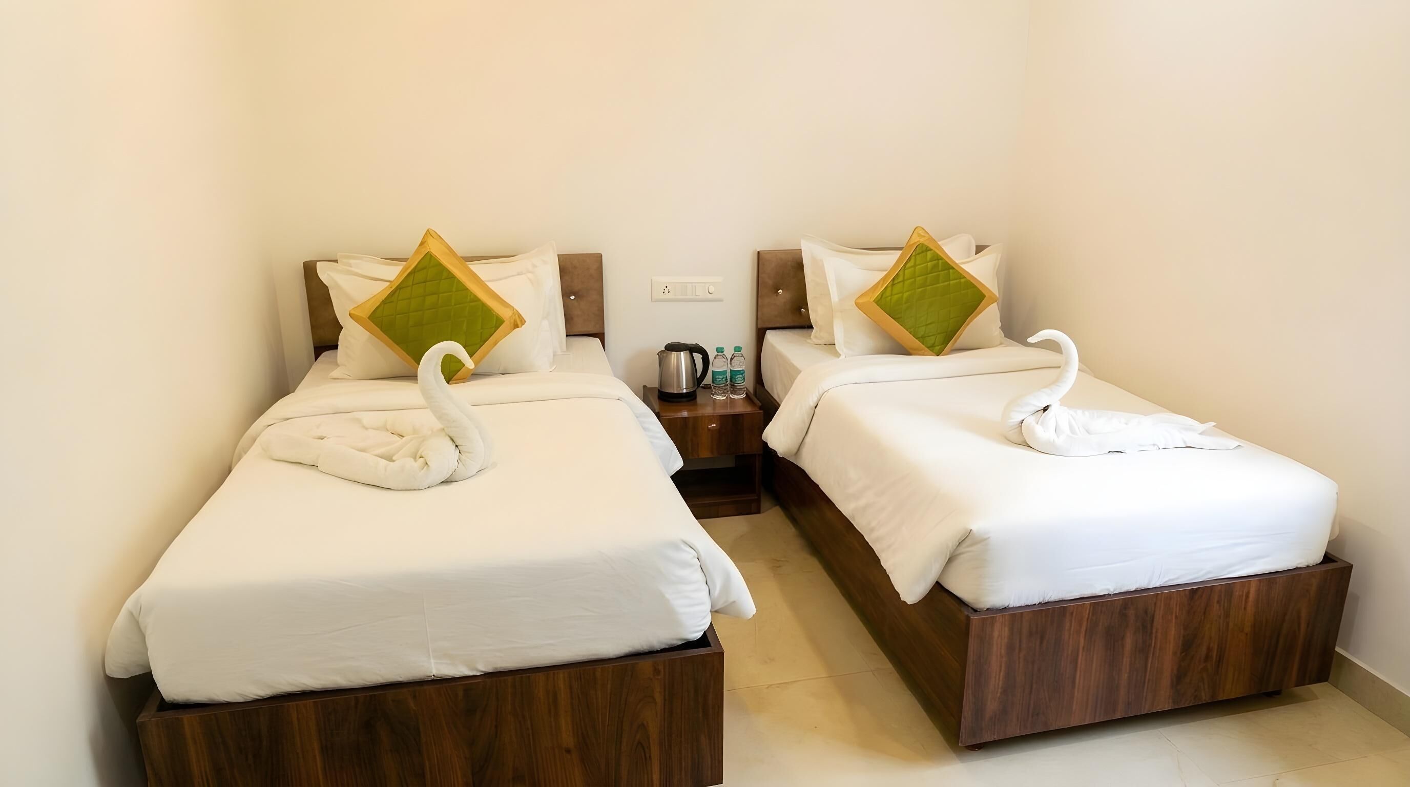 Two single beds with wooden headboards, white bedding, and decorative swan pillows.