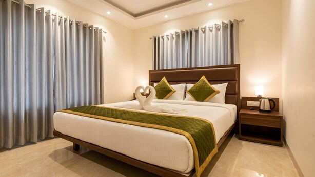A hotel room with a large bed, a nightstand, and curtains.