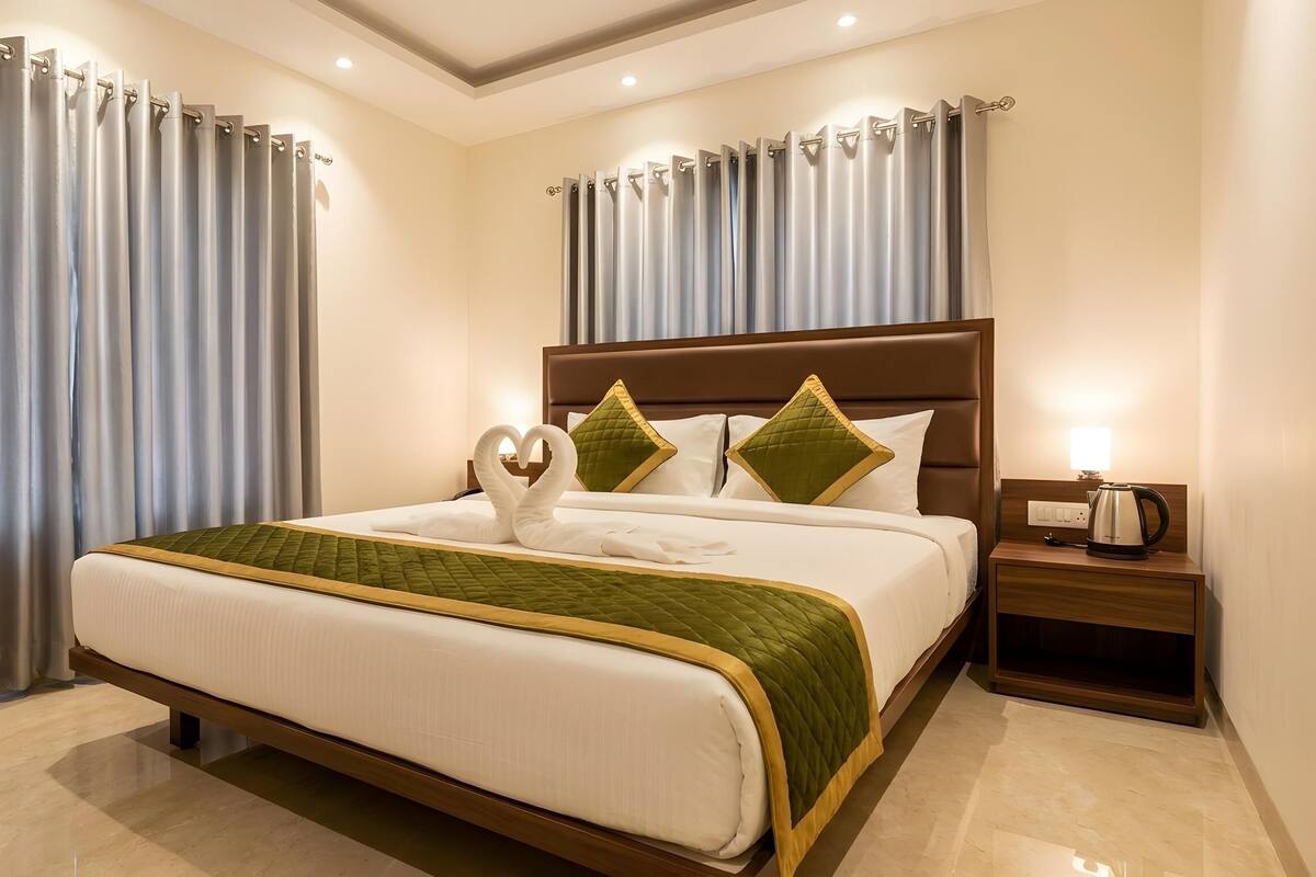 Une chambre d’hôtel avec un grand lit, une table de chevet et des rideaux.